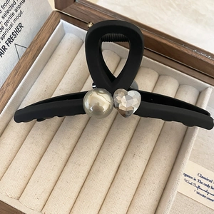 Detail of matte black square hair claw with a white pearl and heart crystal in a gift box