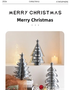 Polished silver metal origami Christmas trees on table with cozy candle decor