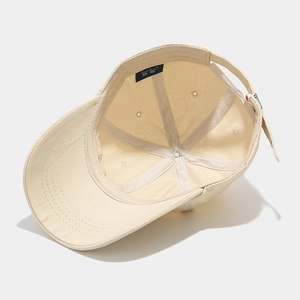 Detailed interior of beige cotton baseball cap showing reinforced seams and adjustable strap