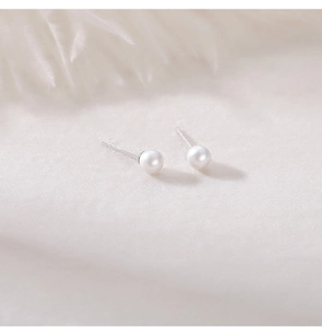 Macro detail of round white pearls on silver studs against a soft feather backdrop