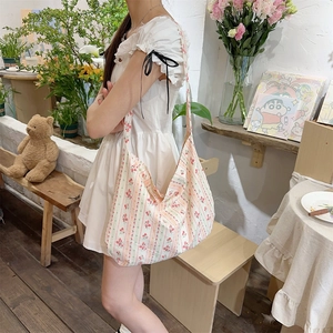 Detailed shot of large floral canvas tote bag with red flowers worn as crossbody bag
