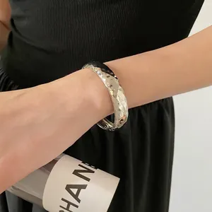 Bracelet jonc argenté minimaliste avec texture géométrique ciselée sur le poignet