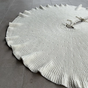 Detail showing off-white knitted Christmas tree skirt with thick wool texture and ties