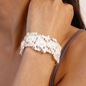 Detailed macro view of vintage matte silver cuff featuring embossed floral patterns