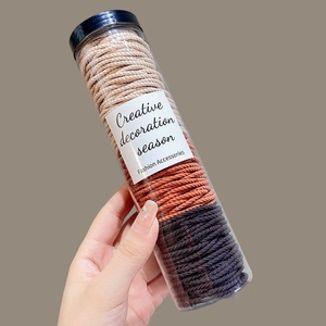 Detailansicht hochelastischer Spiral-Haargummis in einem Behälter in Beige- und Grautönen