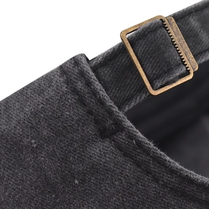Macro detail of bronze metal adjustable buckle on washed dark grey cotton baseball cap