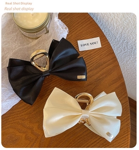 Detail of black and beige satin bow hair claws with elegant gold metal clips