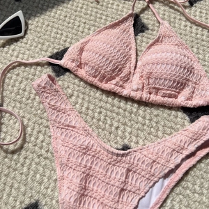 Flat lay of pink smocked texture bikini set with drawstring details and sunglasses