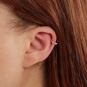 Close-up of a gold S925 sterling silver ear cuff with a sparkling tiny gemstone