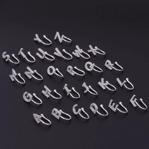 Set of 26 silver alphabet faux nose rings with micro-paved zircons on black background