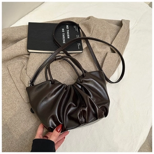 Detail of deep brown pleated leather texture on a stylish cloud-shaped tote handbag