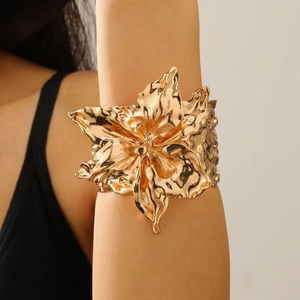Makroansicht der übergroßen goldfarbenen Blumen-Armspange mit glänzendem Spiegeleffekt