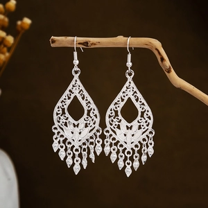 Bohemian silver drop earrings with hollow leaf pattern and tassel charms on wood branch