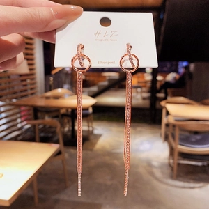 Détail de boucles d'oreilles pendantes or rose avec pompons et zircons brillants