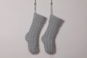 Detail view of two grey knitted Christmas stockings with classic cable stitch patterns