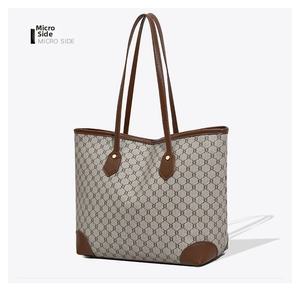 Detailed side view of large tote bag with vintage monogram pattern and brown leather straps