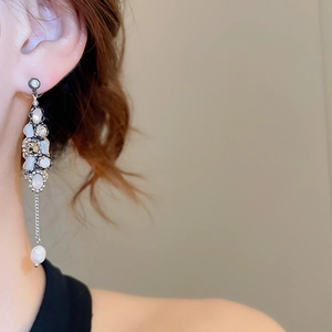 Detail view of long tassel earrings with opal stones and teardrop pearl on model