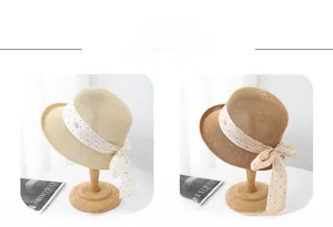 Détail de chapeaux en paille avec rubans à pois et nœuds en kaki et blanc cassé
