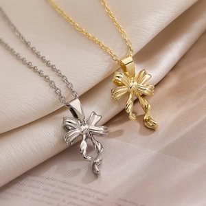 Minimalist bow pendant necklaces in silver and gold finishes on soft fabric