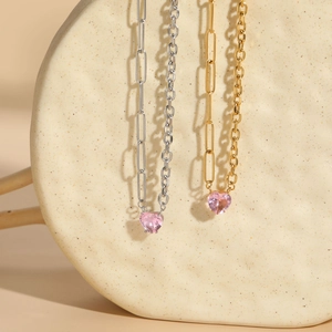 Détail de colliers or et argent avec zircon rose en forme de cœur et maillons trombones