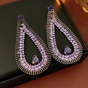 Macro detail of tear-drop earrings with purple crystals and zircons on a dark background