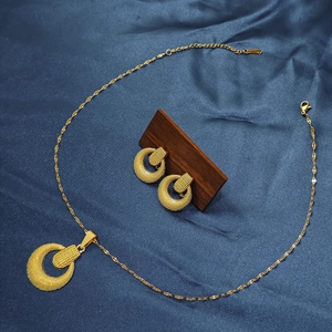 Close-up of matte gold geometric jewelry set with round necklace and earrings on silk
