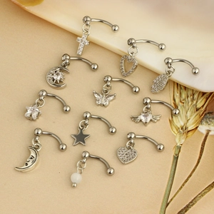 Detailed flat lay of stainless steel butterfly and cross piercing jewelry with zircons