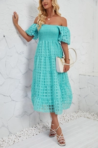 Close-up of textured turquoise fabric with geometric patterns on a tiered summer dress