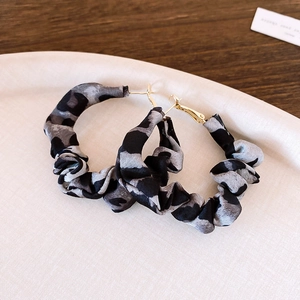 Detailed close-up of C-shaped earrings with leopard print fabric wrap and gold hardware