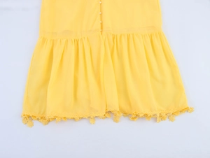 Detailed view of yellow chiffon dress hem featuring lace trim and white pearl buttons