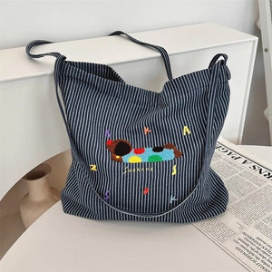 Detail of navy stripe canvas bag featuring colorful embroidery and SUZAKKA text