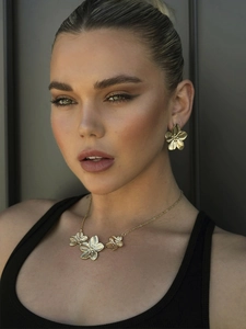 Detail of golden flower jewelry set with brushed metal texture on neck and ear