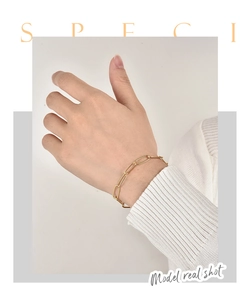 Detailaufnahme eines goldenen Büroklammer-Kettenarmbands mit Strasssteinen am Handgelenk
