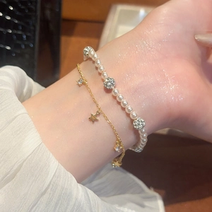 Close-up of double-layer bracelet with pearls, zircon stars and gold chains on wrist