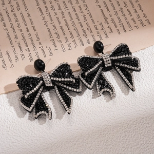Close-up of gothic black bow earrings with rhinestones on a vintage book page