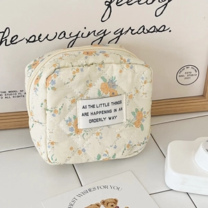 Detail view of quilted floral storage pouch with stylish English label on white tile surface
