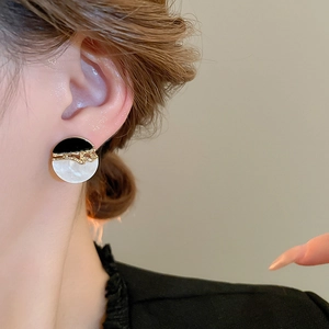 Gros plan d'élégantes boucles d'oreilles rondes en résine bicolore sur un mannequin