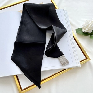 Close-up of black silk scarf with sparkling rhinestone buckle on elegant white background