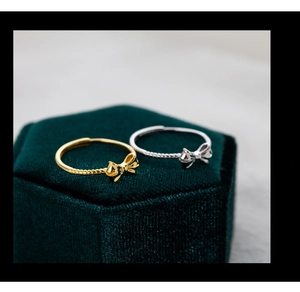 Macro shot of silver and gold bow rings displayed in a luxury green velvet jewelry box