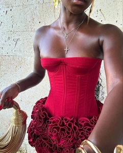 Détail du haut bustier en satin rouge avec baleines et ourlet à volants et bijoux dorés