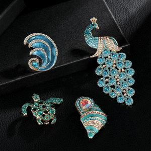 Detailed view of turtle and peacock brooches with rhinestones on black textured background