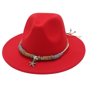 Dettaglio cappello fedora rosso con bobine metalliche e ciondolo a stella marina