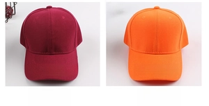 Detail view of cotton baseball caps in burgundy and orange with reinforced stitching
