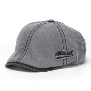 Detail of gray washed denim newsboy cap featuring a Natural embroidered side patch