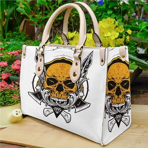 White PU leather tote bag with skull print and gold hardware on a wooden platform