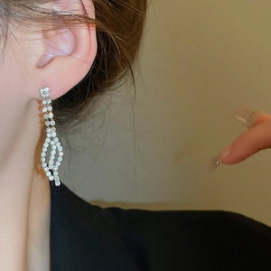 Macro detail of silver-toned leaf-inspired earrings with sparkling inlaid rhinestones
