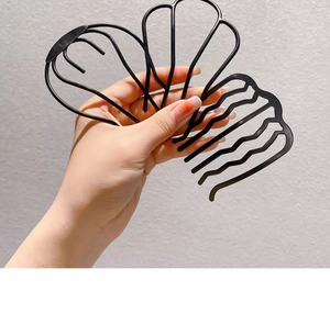 Detail of wavy black hair comb clip held by a hand for easy bun styling accessory