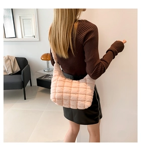 Detail of light pink quilted puffer bag with soft texture and glossy nylon fabric