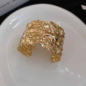 Detail view of gold wide open cuff bracelet with hammered pleated metallic texture