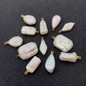 Detailed view of assorted baroque freshwater pearl charms with golden loops on black texture